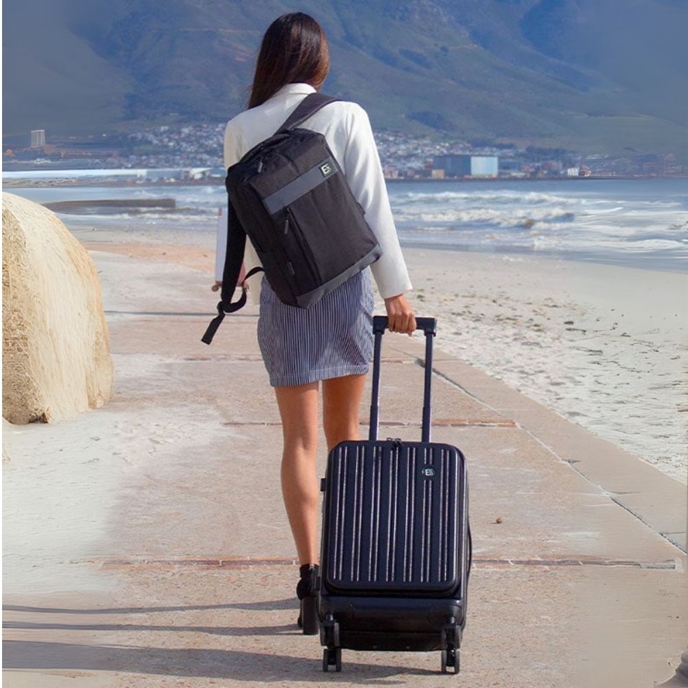 Woman walking along beachfront with Seattle eco-friendly luggage and backpack β lifestyle product image 01
